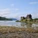 a rocky shore next to a body of water with a castle in the background